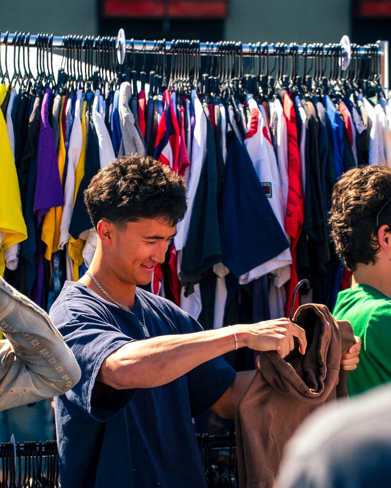 A shopper smiling while holding a hoodie he pulled from the rack