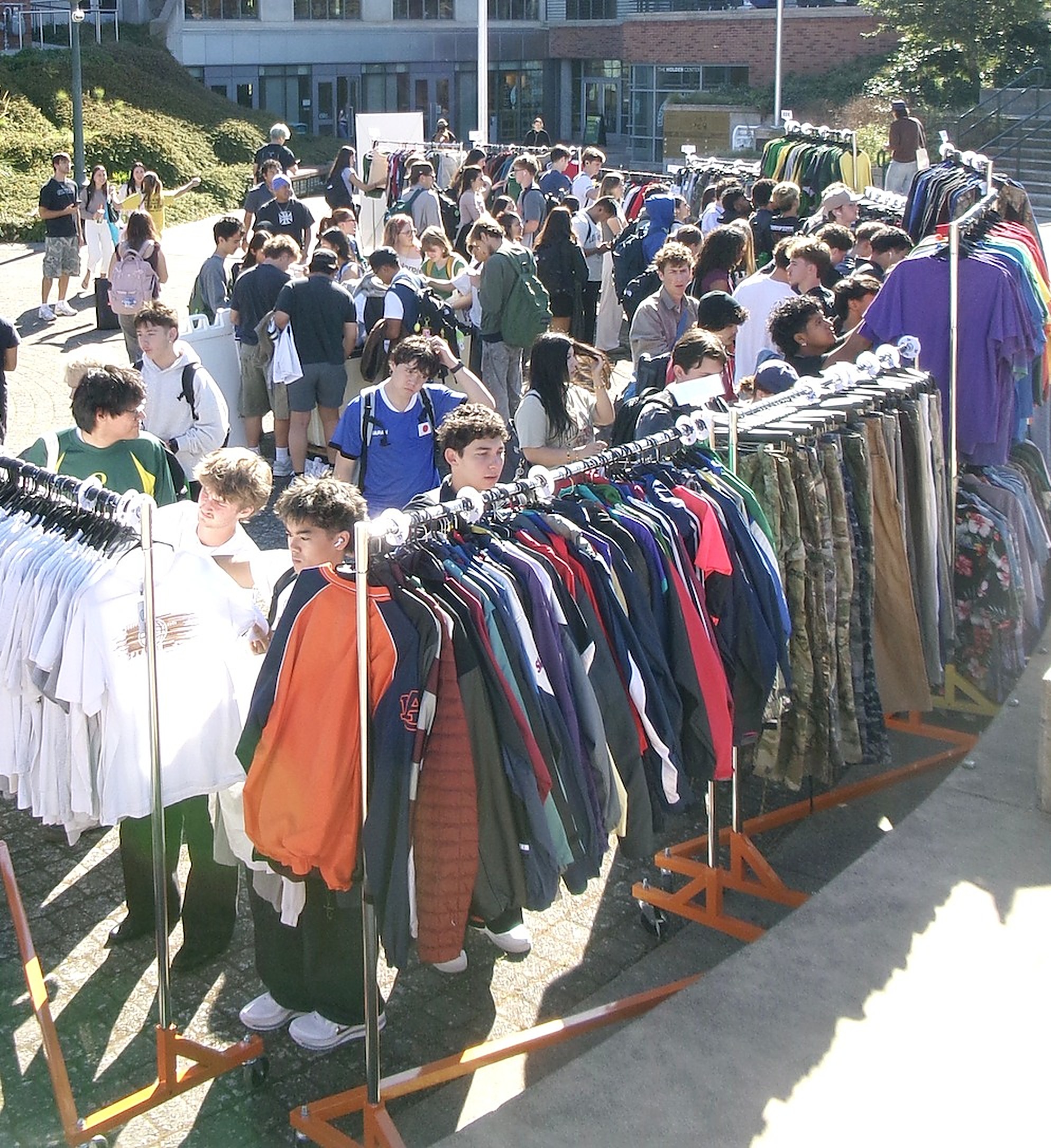 Shoppers working their way down long rows of racks at a daytime FoundF1rst market