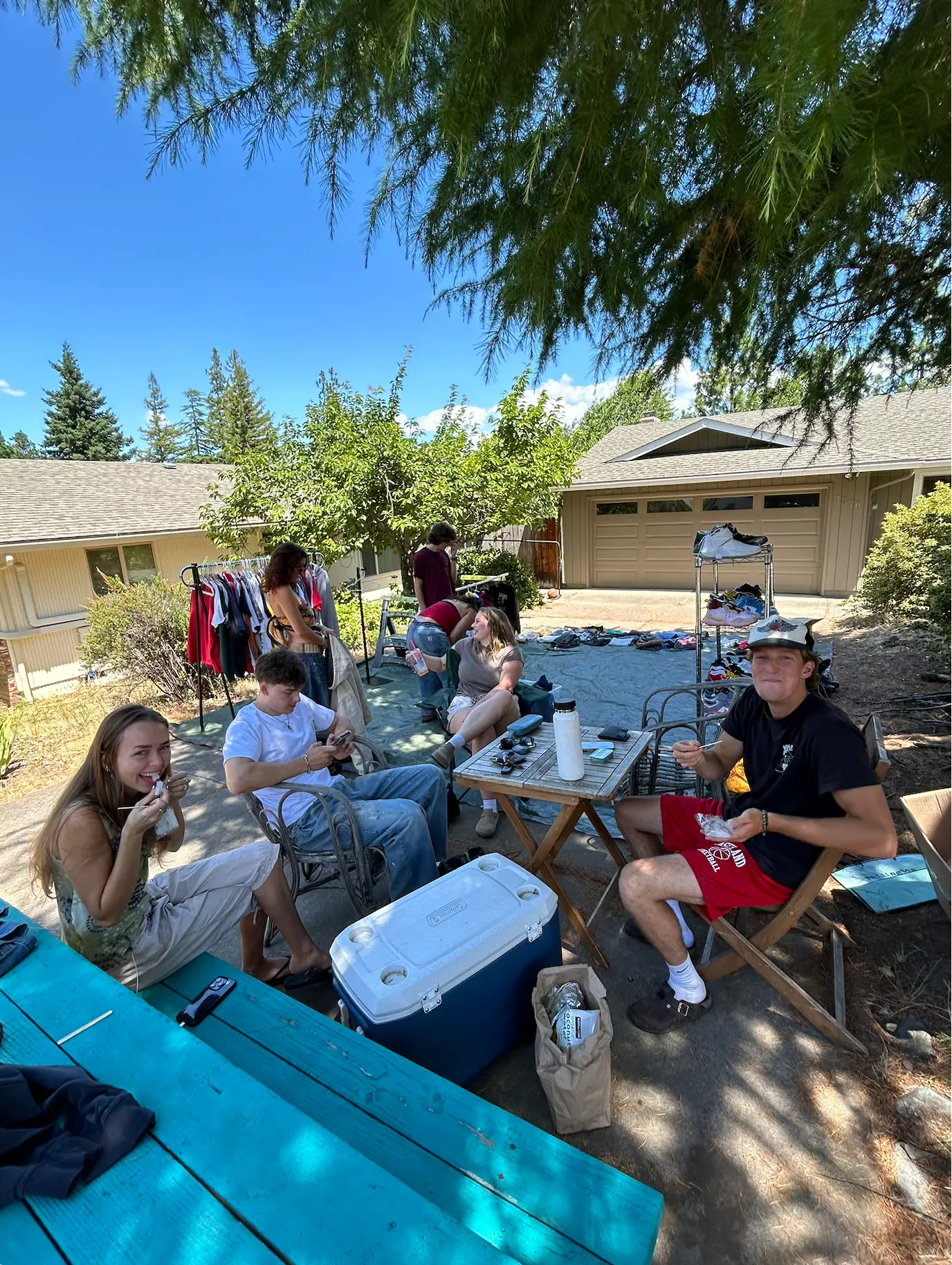 Friends hanging out around the racks and gear laid out at a FoundF1rst driveway pop-up